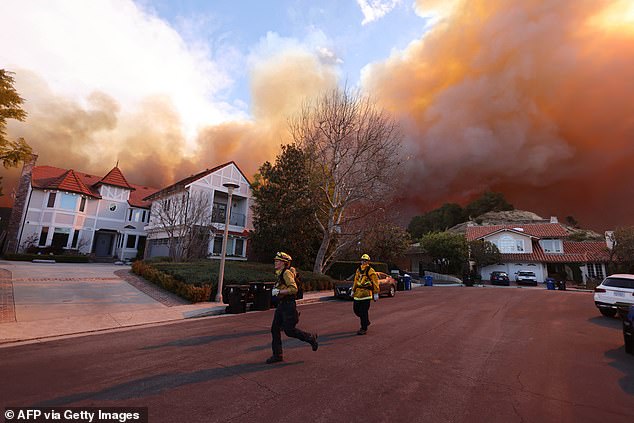Firefighters run as a brush fire burns in Pacific Palisades, California
