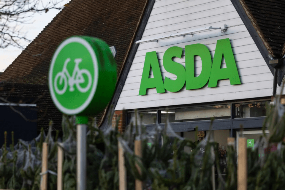 A green bicycle sign with the ASDA logo on a building in the background.
