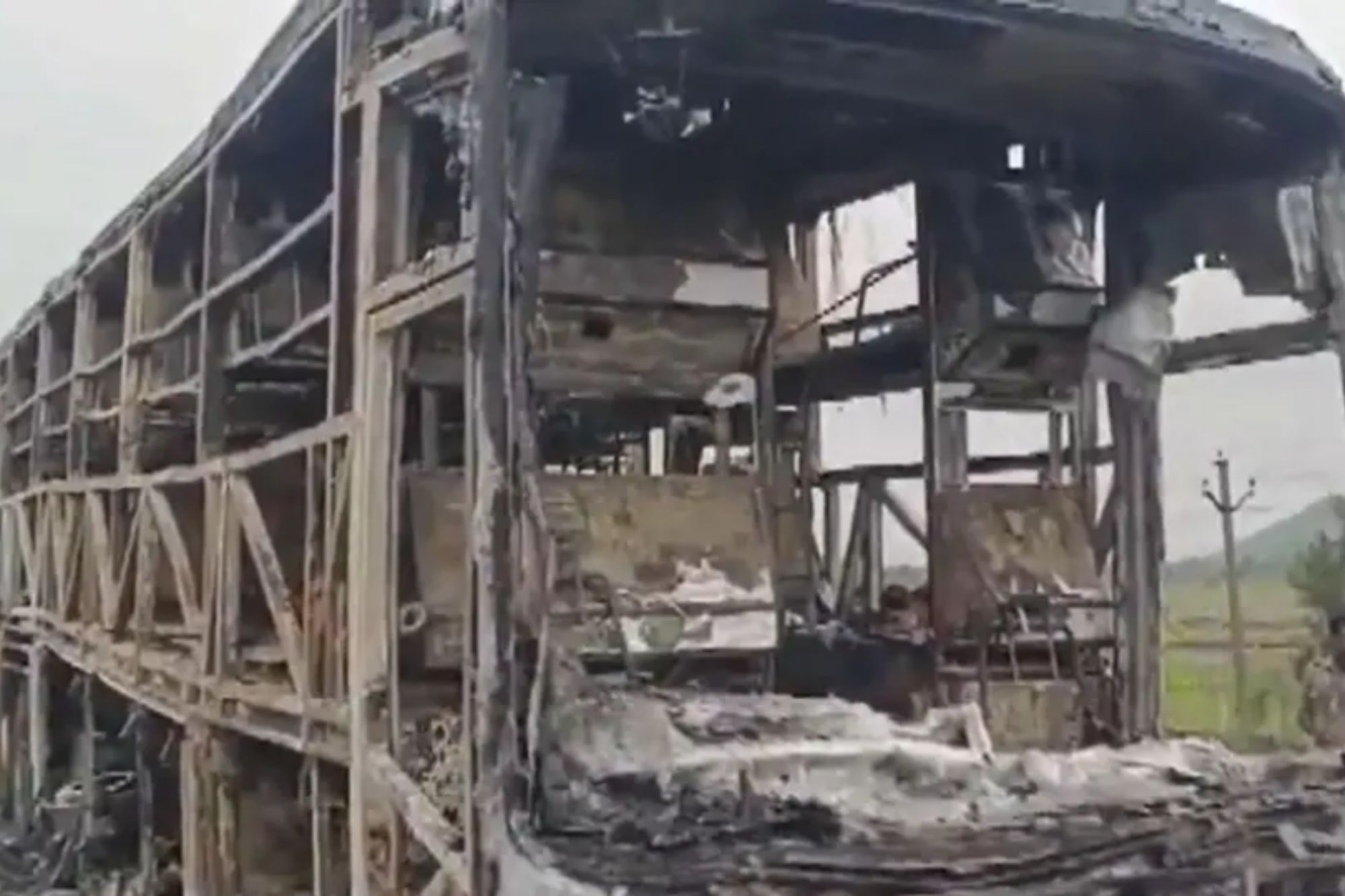 An image collage containing 1 images, Image 1 shows Remains of a burned-out bus, charred to its skeletal frame, are seen from the side and front