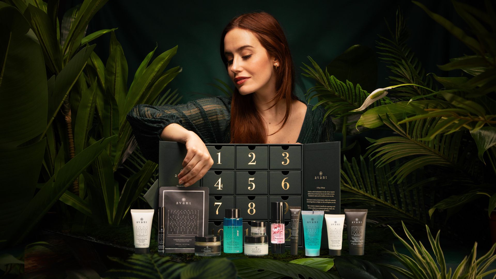A woman opens a drawer of an Avant 12-day beauty advent calendar, revealing various skincare products.