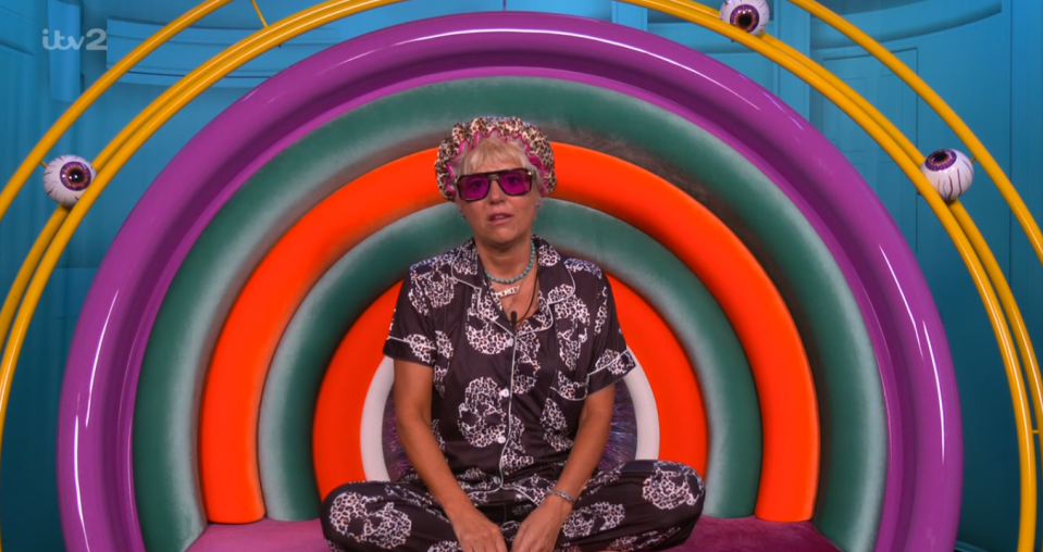 Caroline sitting in a rainbow-colored chair wearing leopard print pajamas.