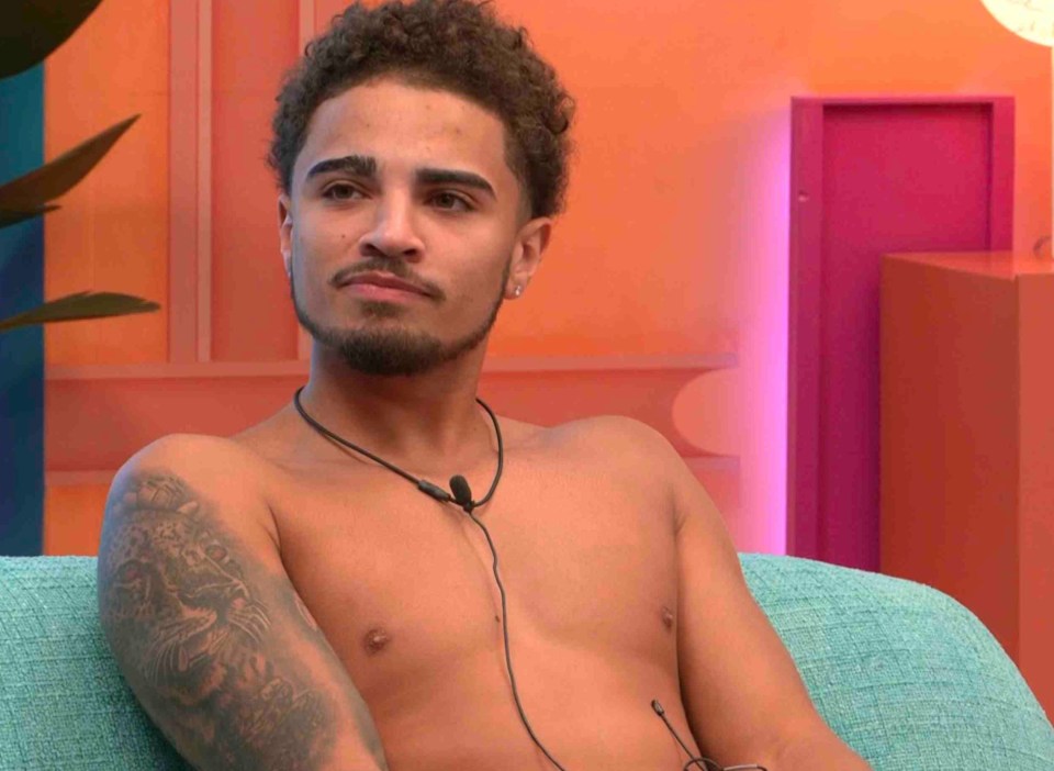 ITV2 Big Brother contestant, George, wearing a microphone and sitting in an armchair.