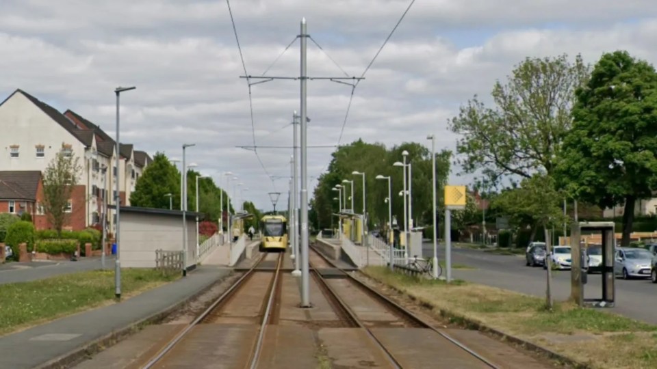 A yellow tram arriving at a station in Manchester, England.