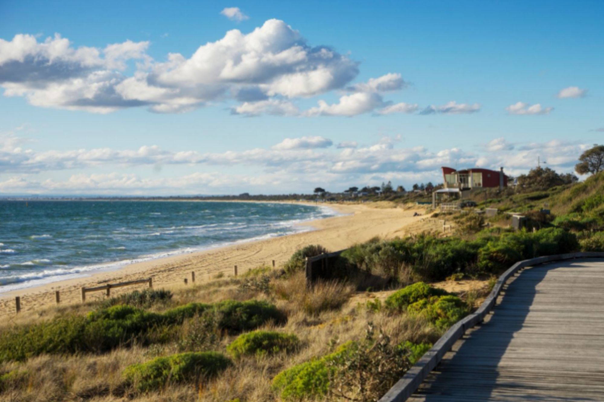 An image collage containing 1 images, Image 1 shows A wooden boardwalk curving along a sandy beach with the ocean to the left and green dunes to the right
