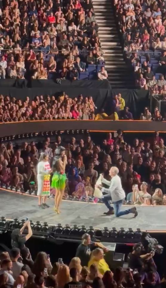 A man on one knee proposing to Katy Perry on stage during a concert.