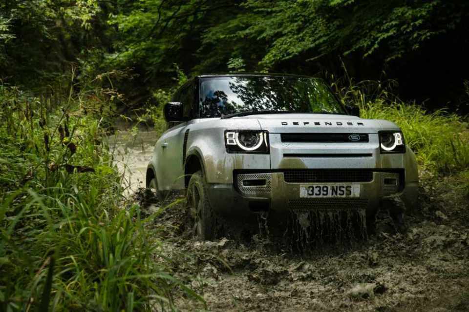 Land Rover Defender 90 in a muddy off-road track.