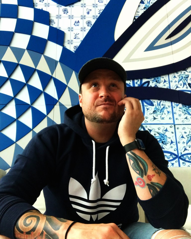 Brooklyn Earick wearing a black Adidas hoodie, cap, and arm tattoos.