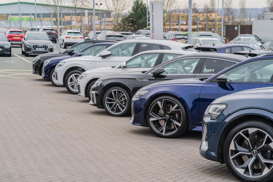 A row of Audis parked at a dealership lot.