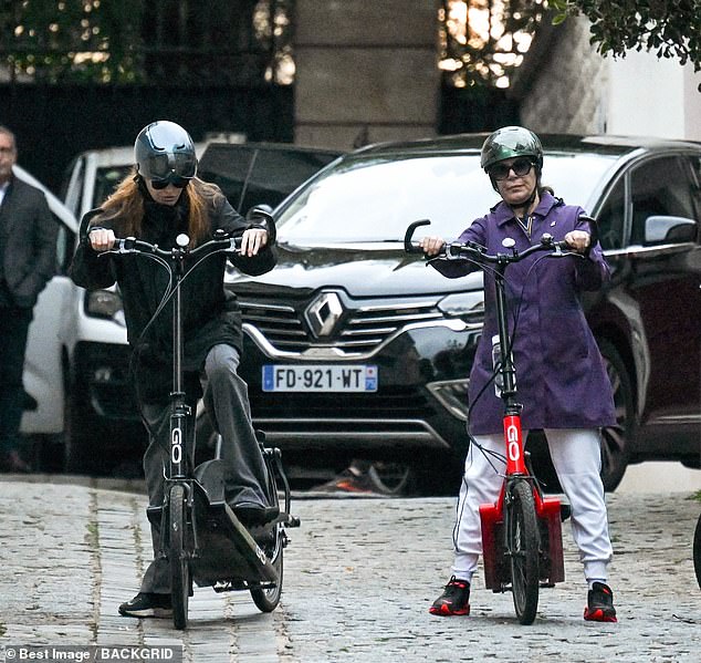 Bruni was seen wearing a black coat and a pair of oversized sunglasses as she rode along a cobbled street with a companion