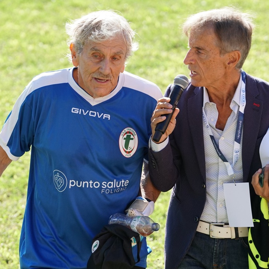 Lamberto Boranga wearing a blue soccer jersey speaking with a man holding a microphone.