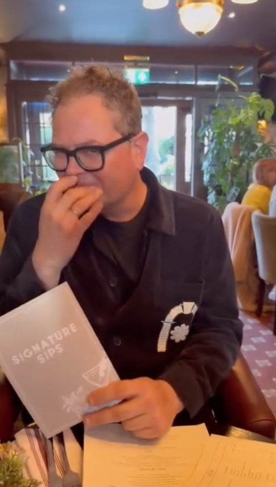 Alan Carr holding a "Signature Sips" menu.