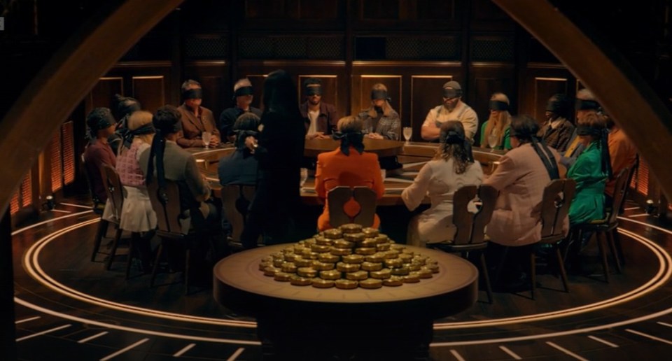 A group of people wearing blindfolds sitting around a circular table, with a table full of gold coins in the foreground.