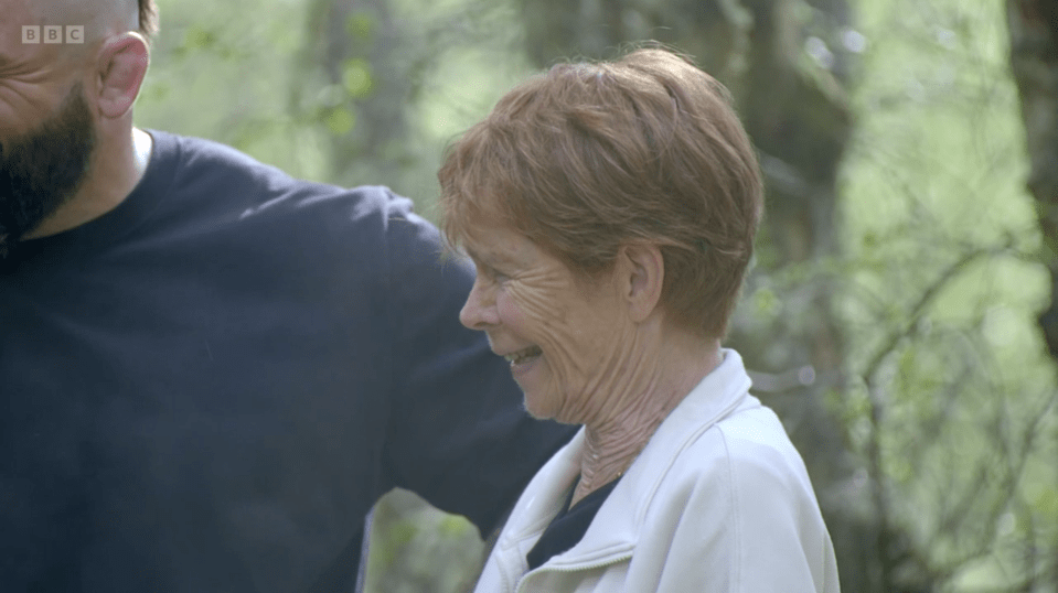 A laughing woman in a white jacket next to a man with a beard and a dark shirt.