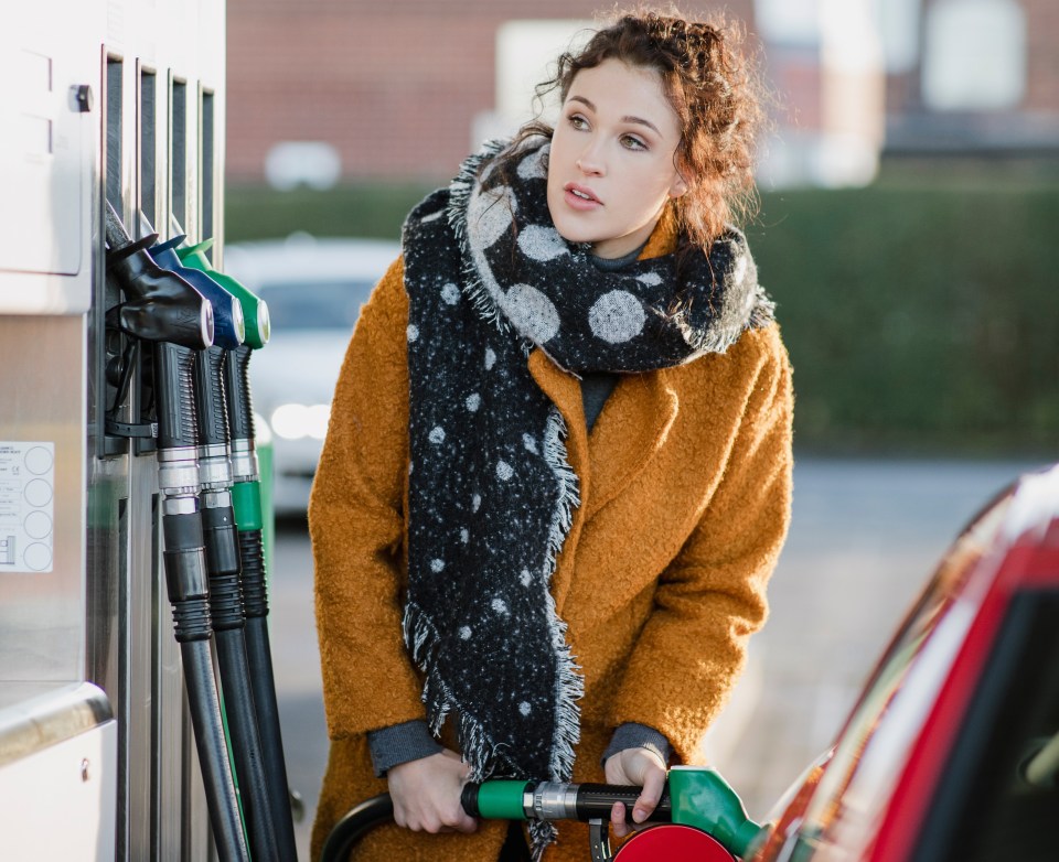 Young businesswoman putting fuel in her car at the petrol station.