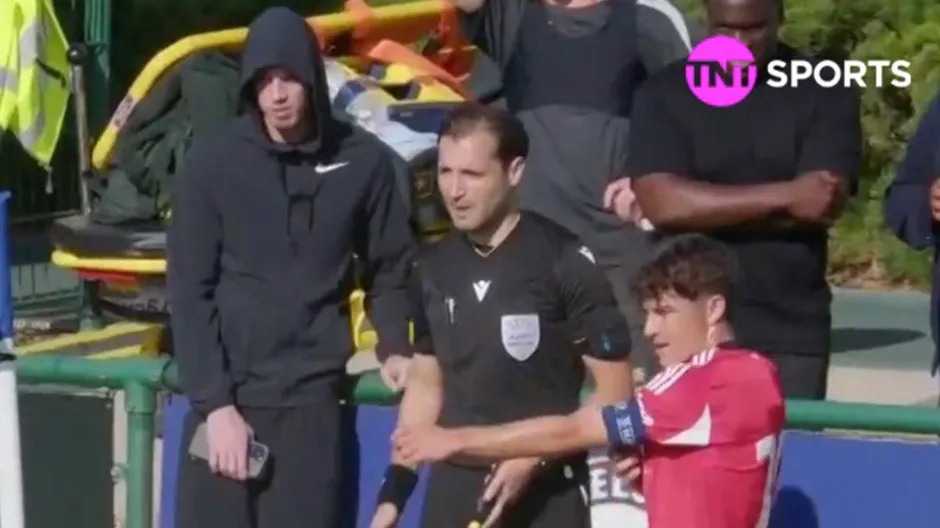 A soccer player in a red jersey getting an arm massage from a referee.