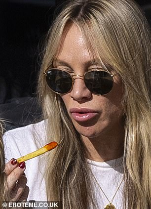The personal trainer, 38, showcased a plumper pout as she indulged in French fries and enjoyed a glass of vino in an outdoor seating area of a restaurant in Hampstead