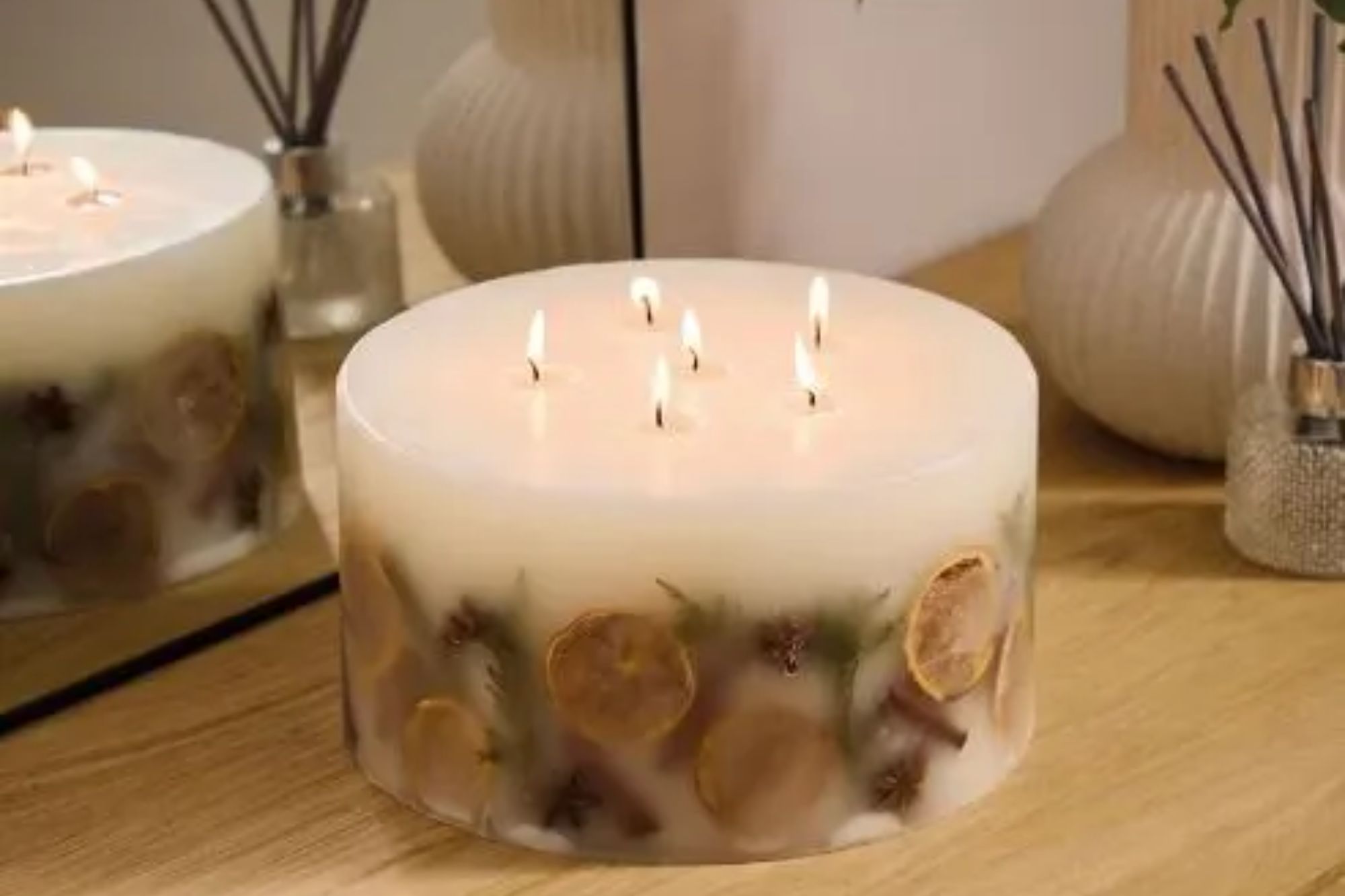 An image collage containing 1 images, Image 1 shows Hotel Collection XXL Inclusion Candle with six lit wicks, dried orange slices, and star anise embedded in the wax