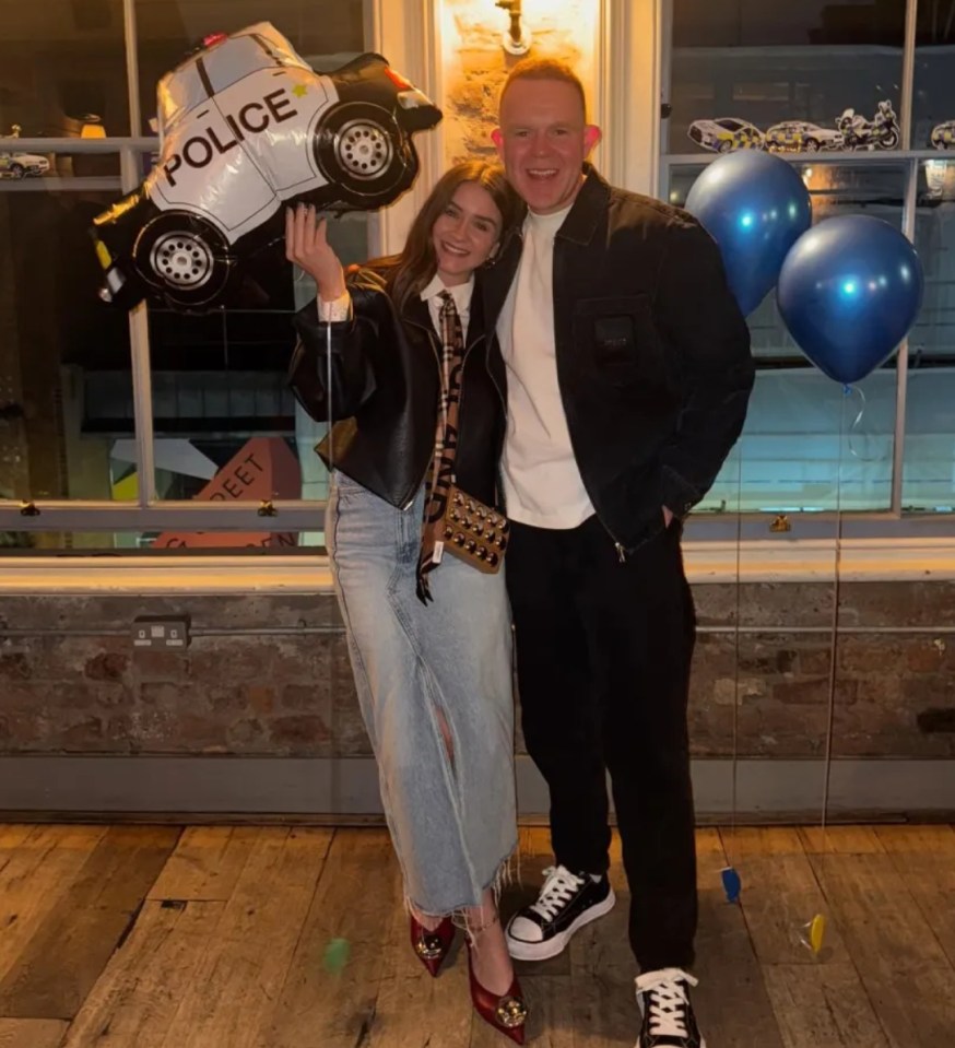 Woman holding a police car balloon and man smiling.