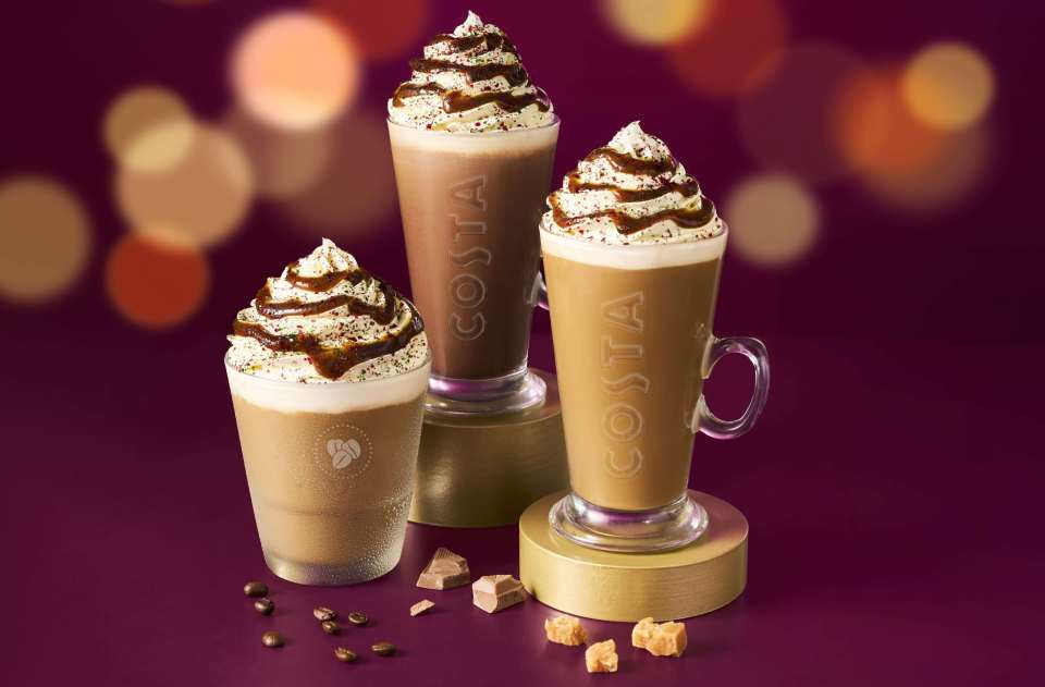 Three Costa Coffee drinks, two of which are topped with whipped cream, chocolate drizzle, and sprinkles.