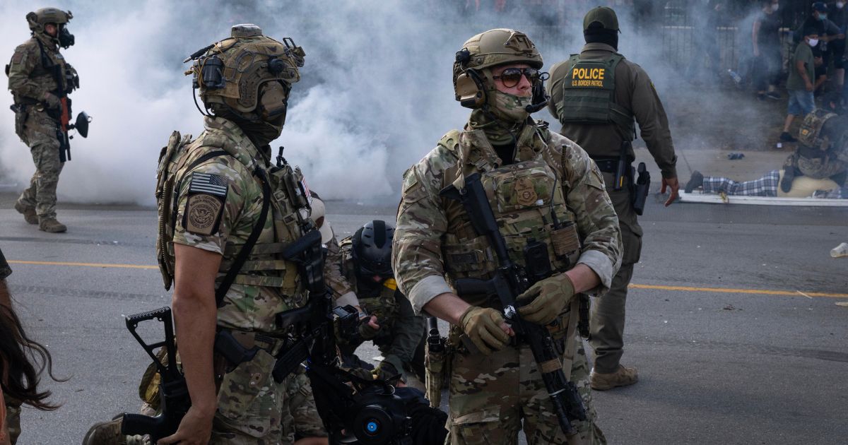 Police take two people into custody as tear gas fills the air after it was used by federal law enforcement agents who were being confronted by community members and activists in the Chicago area.