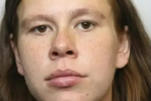 A headshot of a young woman with long, light brown hair, light brown eyes, a neutral expression, and freckles across her nose and cheeks.