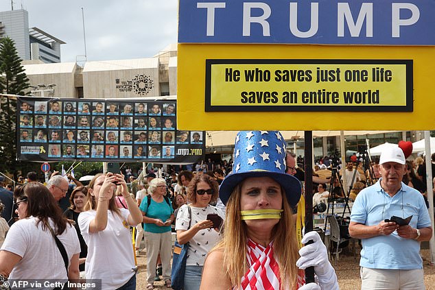 A woman in the colours of the US flag holds up a placard thanking US President Donald Trump in Tel Aviv's Hostage Square on October 9, 2025, following the announcement of a new Gaza ceasefire deal