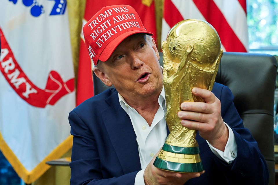 Donald Trump wearing a red "Trump Was Right About Everything!" hat while holding the FIFA World Cup trophy.