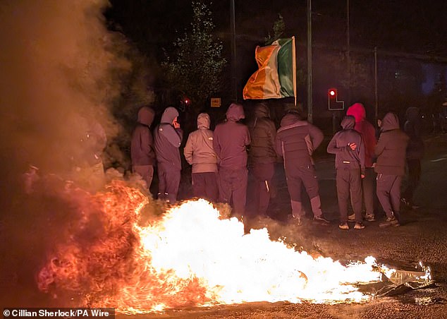 Masked men wearing balaclavas (pictured) set objects alight near the hotel on October 21 as the riots erupted