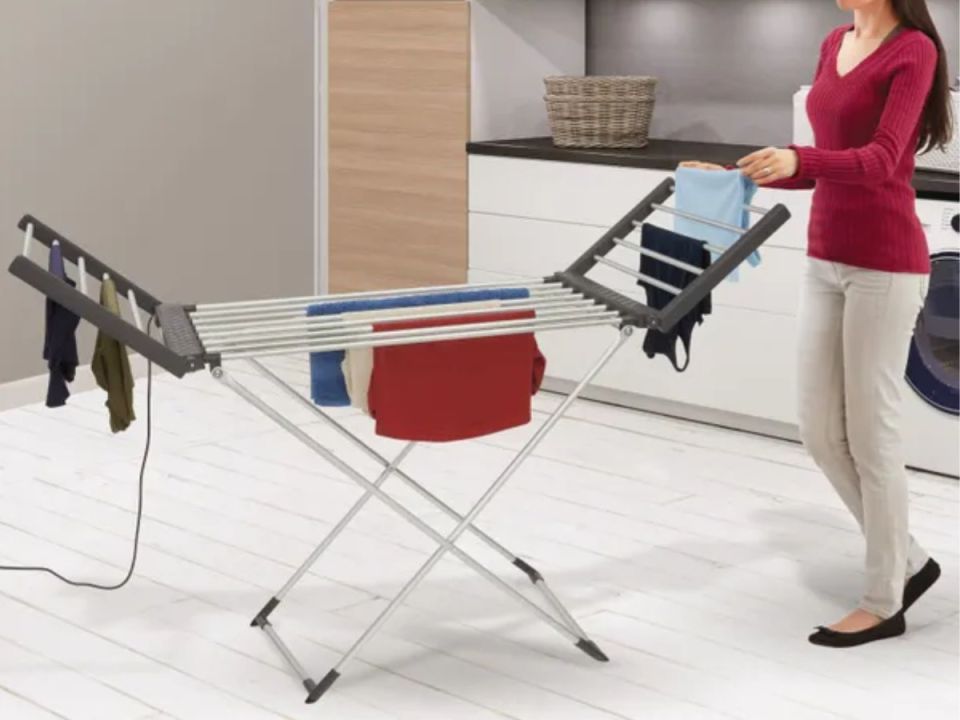 A person hanging laundry on a heated drying rack.