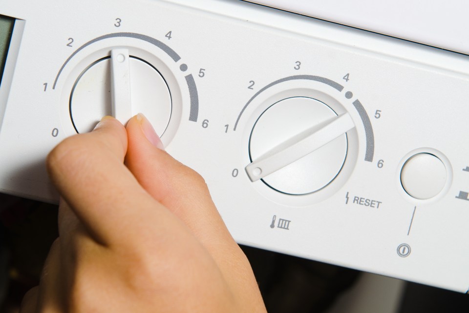 Close-up of a hand turning dials on a central heating boiler