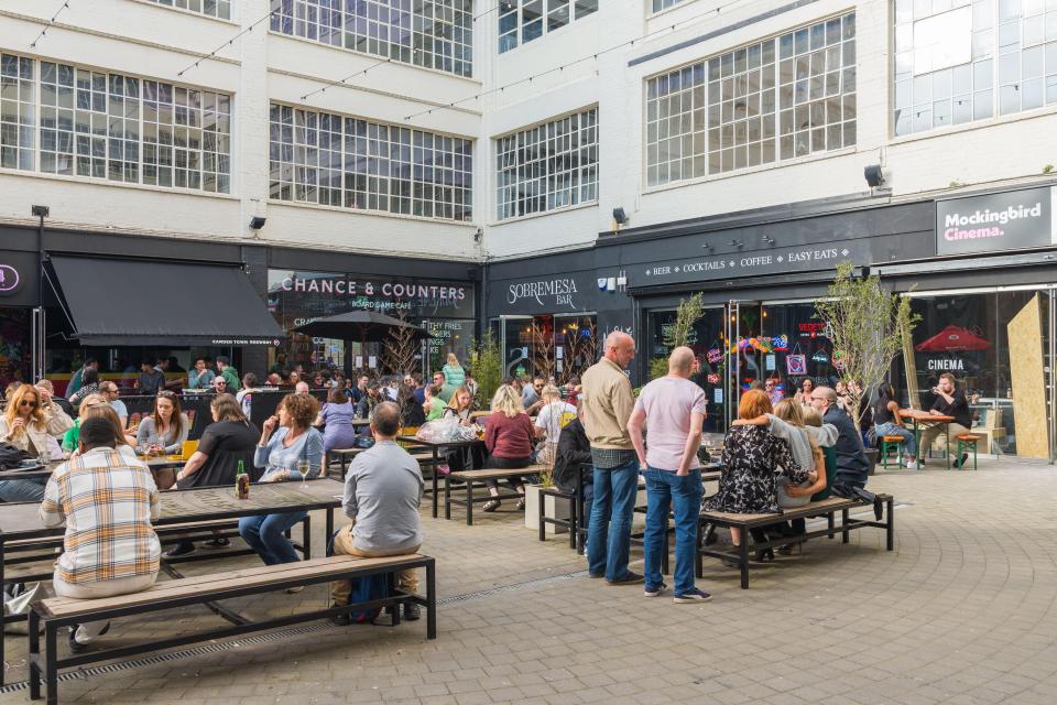 People sitting and standing in the courtyard of The Custard Factory in Digbeth, Birmingham.