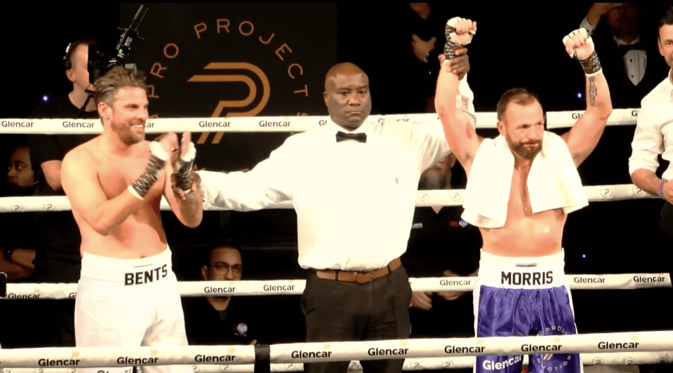 Referee raising Morris's hand in victory over Bents in a boxing ring.
