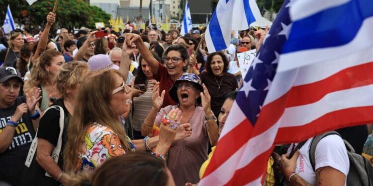 Israelis celebrate with Israeli and American flags as they react to the news of the Gaza peace deal at Hostages Square in Tel Aviv, Israel, on Thursday.