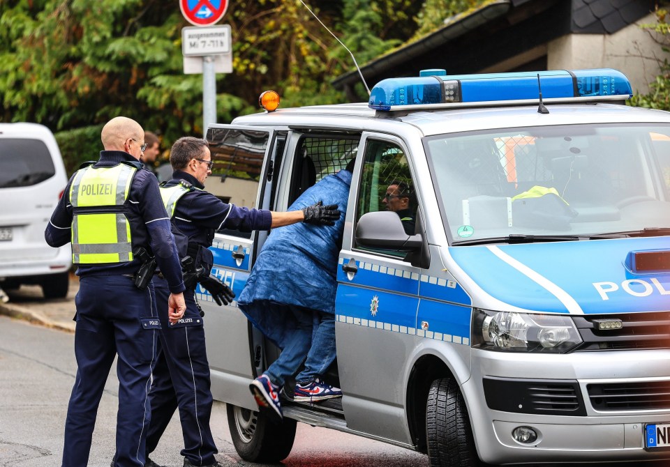 Police officers placing a teenager into a police car.