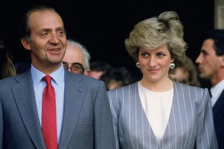 King Juan Carlos, Princess Diana, and Queen Sofia standing together, each holding a bouquet of flowers.