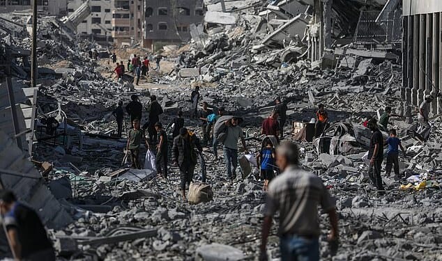 The Israeli military has said the ceasefire agreement with Hamas came into effect at noon local time (10am BST), and that troops are withdrawing to the agreed-upon deployment lines. Pictured: Palestinians walk along a street amid the rubble of destroyed buildings during a ceasefire between Israel and Hamas