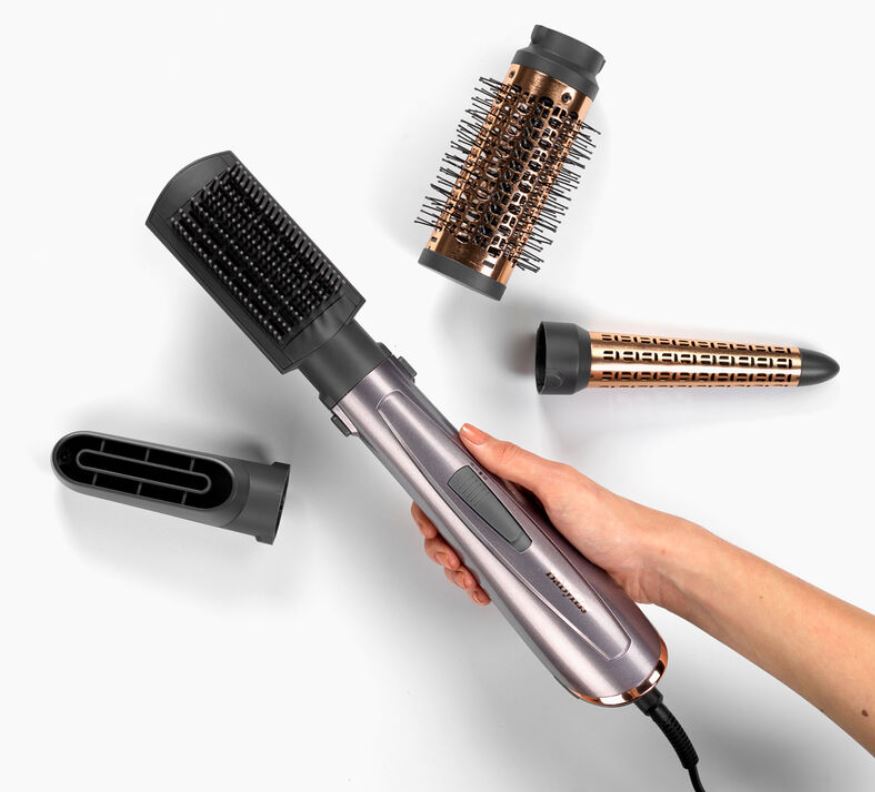 BaByliss hot air styler with interchangeable attachments, held by a hand.