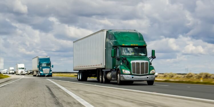 A green truck driving on Interstate 5 in California.
