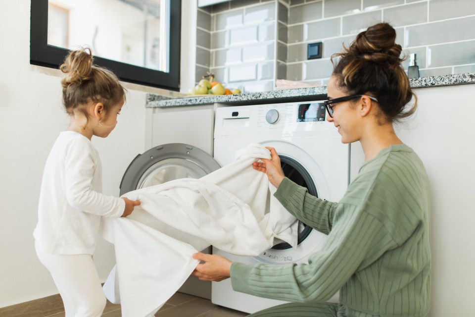 Mother and daughter loading laundry into the washing machine.
