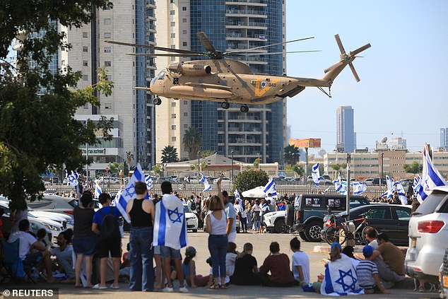 People watch a helicopter, on the day of hostages-prisoners swap, during a ceasefire deal in Gaza between Hamas and Israel, at Rabin Medical Center-Beilinson Hospital, in Petah Tikva, Israel October 13, 2025