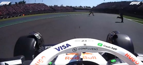 POV from a Formula 1 car approaching people on the track.