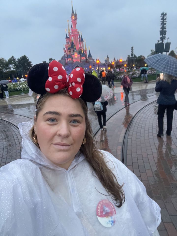 Cydney Fulker at Disneyland Paris wearing Minnie Mouse ears and a white poncho.