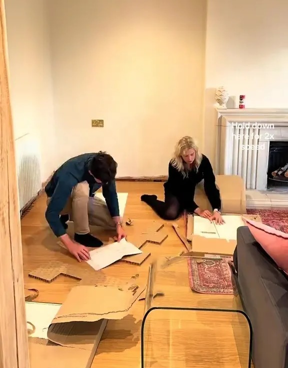 Two people building alcove units on the floor in a room.