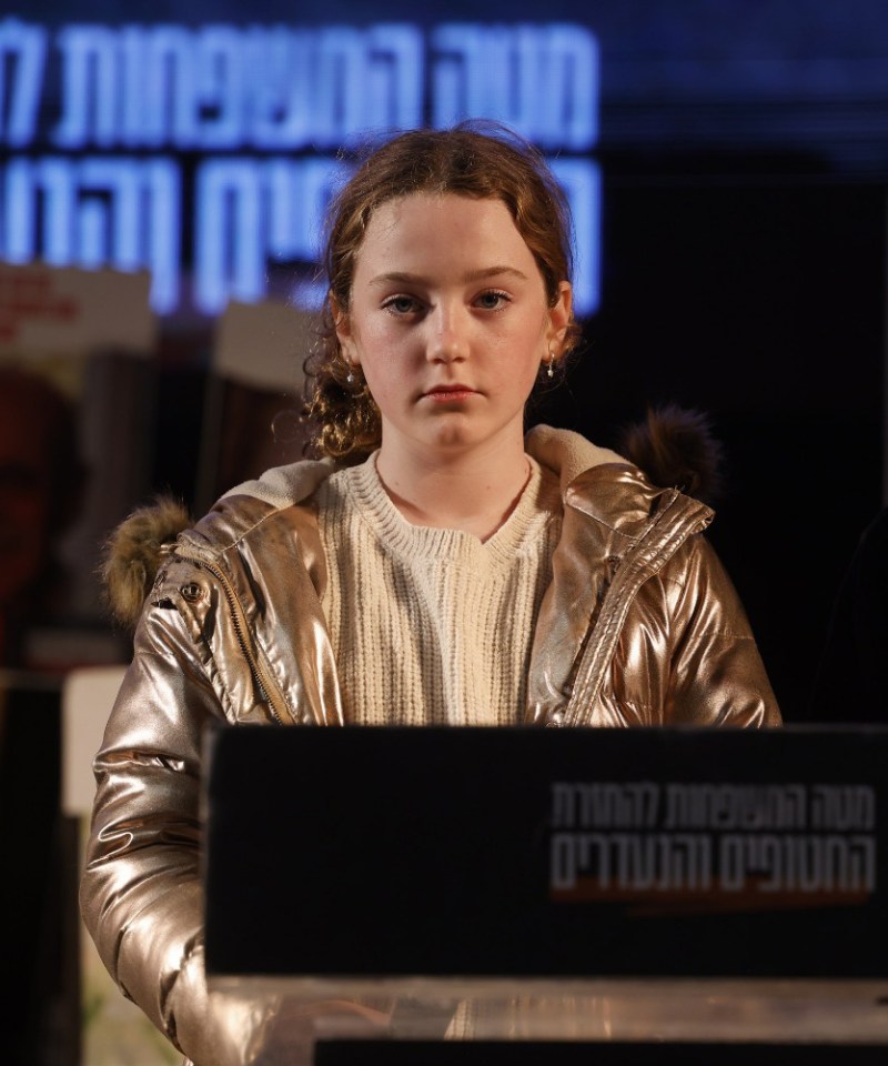 Former hostage Emily Hand standing in front of a podium during a rally in Hostage Square in Tel Aviv.