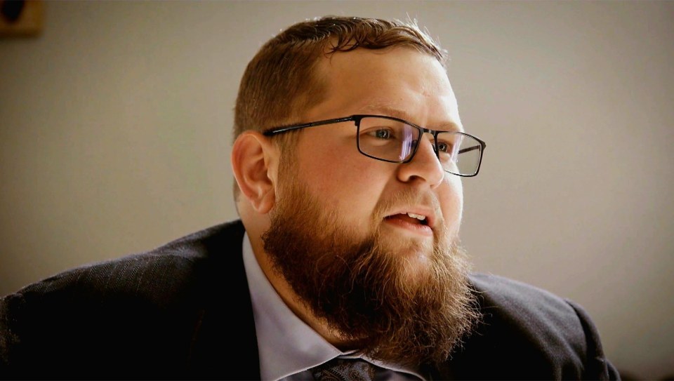 A man with a beard and glasses looking to the right.