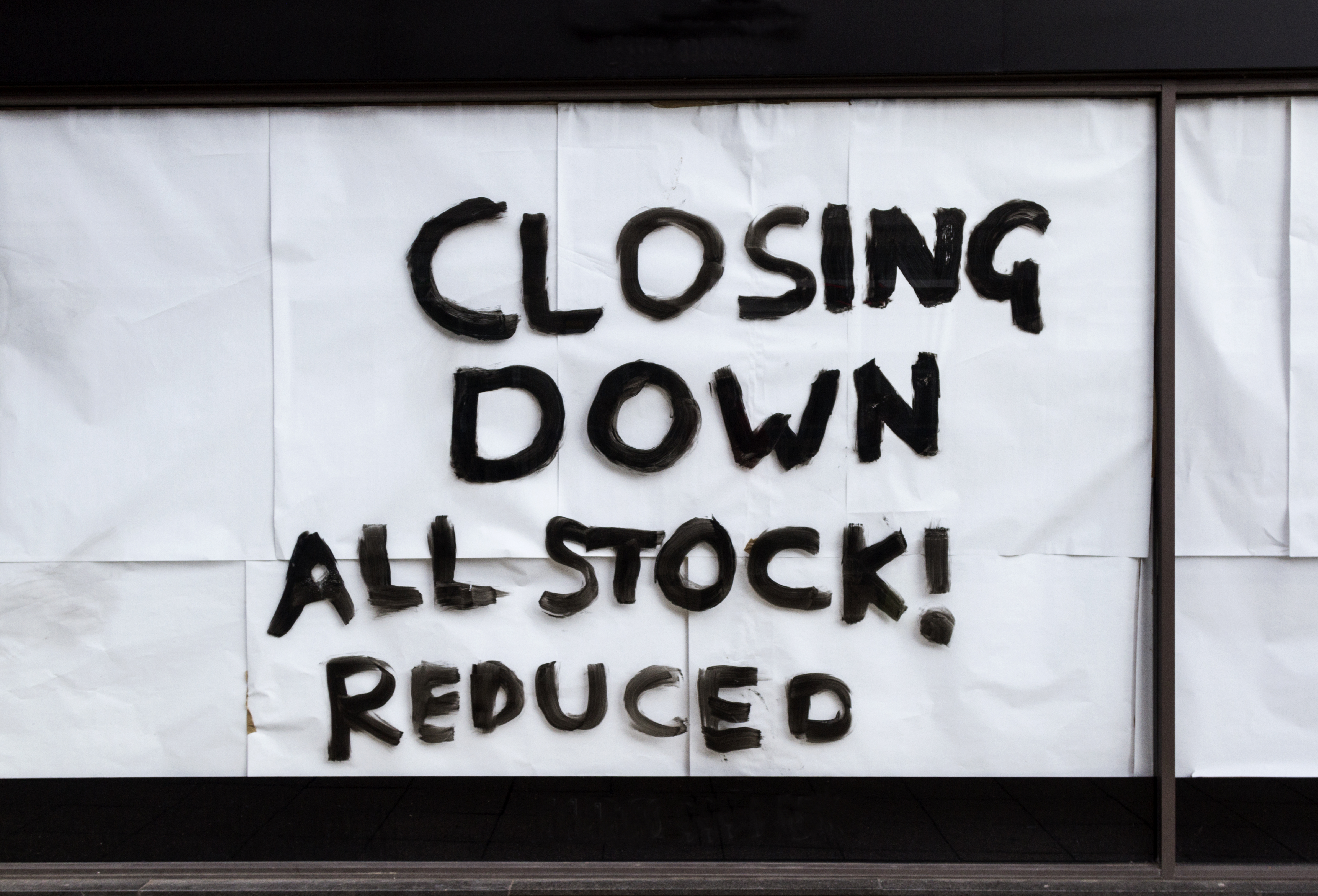 Store window in Sheffield, UK, with a handwritten sign that reads "CLOSING DOWN ALL STOCK! REDUCED".