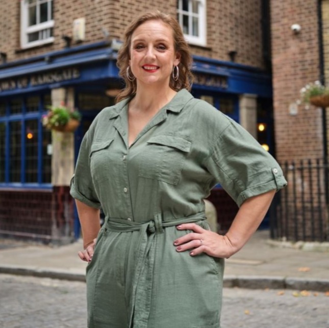 Woman in a green jumpsuit standing in front of a pub.