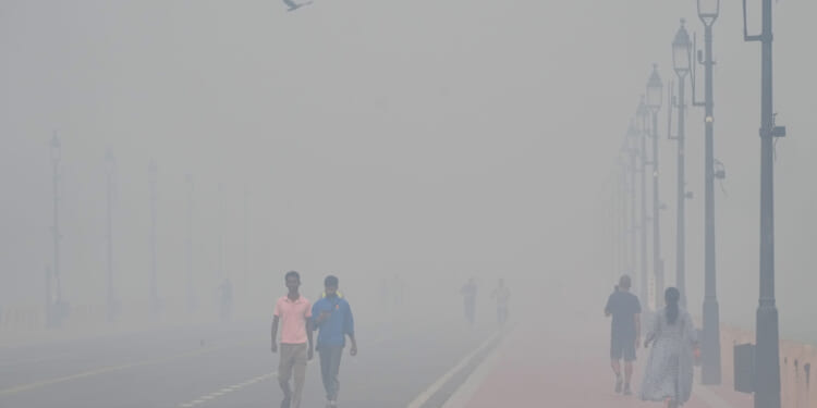 People walk near the India Gate monument Tuesday morning amid smog a day after Diwali festival in New Delhi, India.