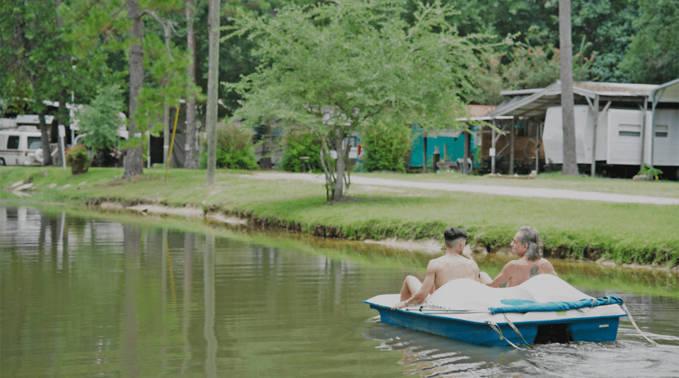 Two men in a pedal boat on a lake at Indian Hills nudist resort.