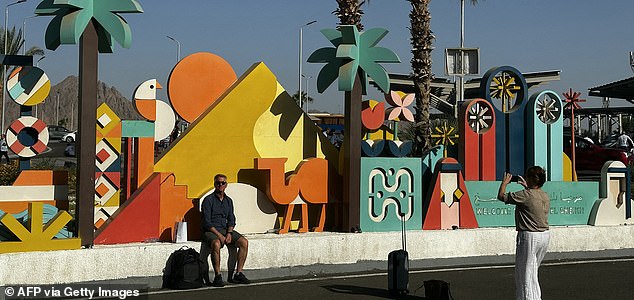 A tourist takes a picture of a man in the Red Sea resort of Sharm el-Sheikh on the southern tip of Egypt's Sinai Peninsula, where Israel and Hamas agreed on October 9, 2025 on a Gaza ceasefire deal that could free the remaining living hostages within days, in a major step toward ending a war that has killed tens of thousands and unleashed a humanitarian crisis. The agreement, to be signed in Egypt, also calls for Israel to release hundreds of Palestinian prisoners as well as prompt a surge of aid into Gaza after more than two years of war started by Hamas's unprecedented October 2023 attack on Israel. (Photo by Khaled DESOUKI / AFP) (Photo by KHALED DESOUKI/AFP via Getty Images)